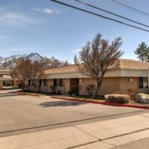 A suburban commercial building with trees and mountains in the background.