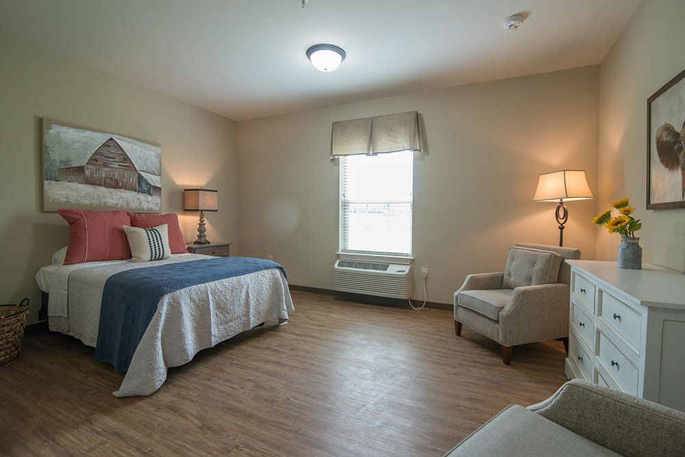 A cozy bedroom featuring a bed, armchair, and soft lighting.