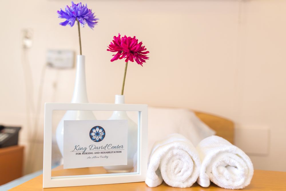 Rolled white towels with flowers in vases, creating a spa-like atmosphere.