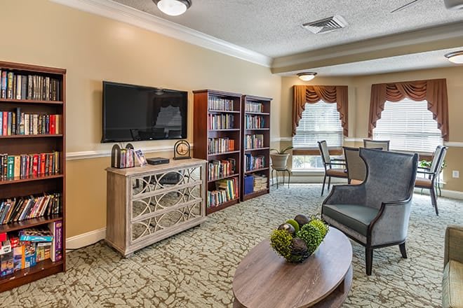 A cozy living room with a television, bookshelf, and comfortable seating arrangement.