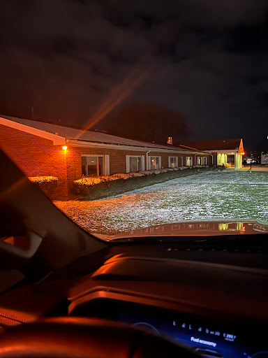 A view of a building at night, illuminated by warm lights, with a snowy landscape in the foreground.