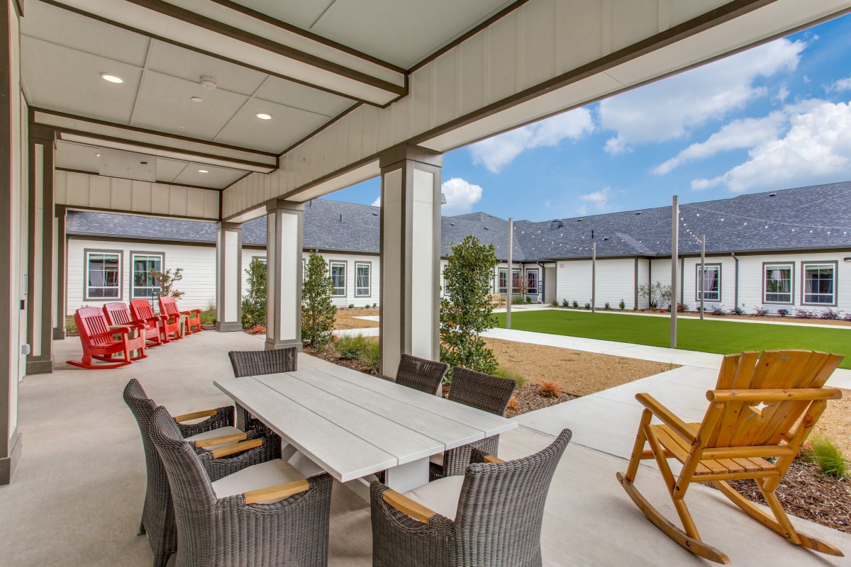 A spacious outdoor patio with a dining table and chairs overlooking a well-maintained garden.