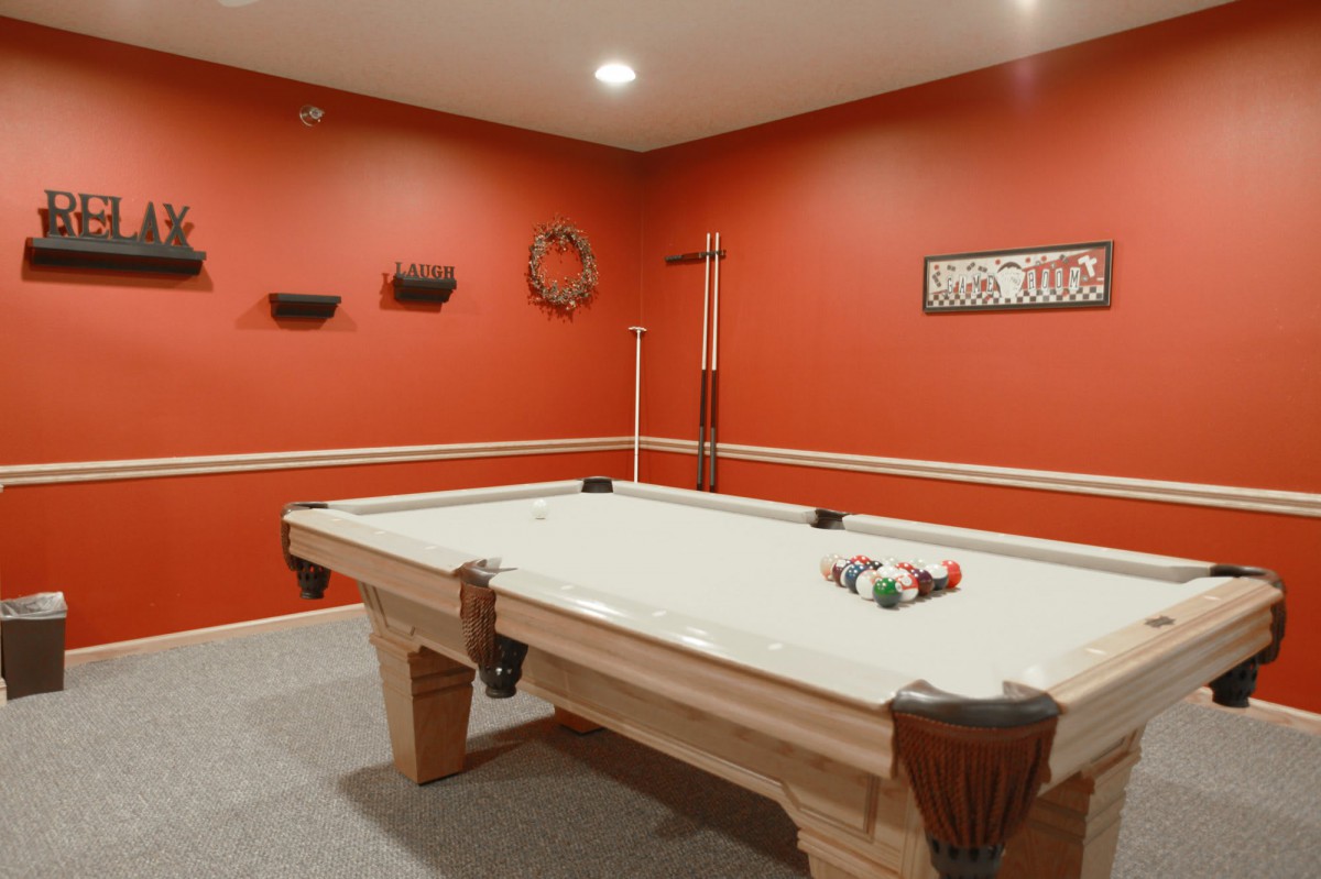 A stylish billiard room featuring a white pool table against striking red walls.