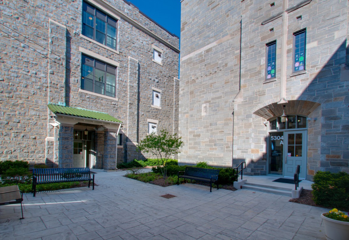 A courtyard surrounded by brick buildings with benches and greenery.