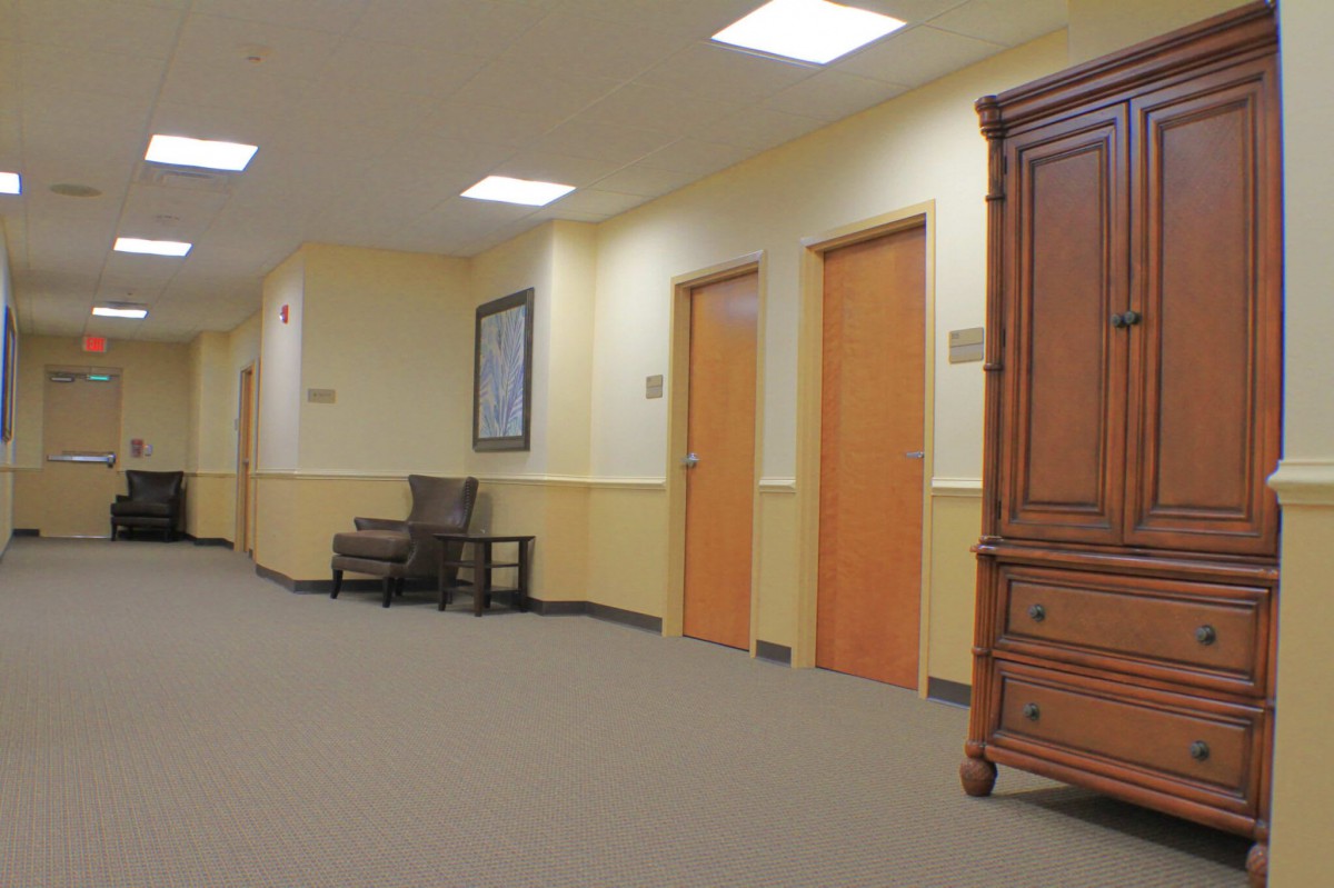 A quiet office hallway with several doors and a wooden cabinet.