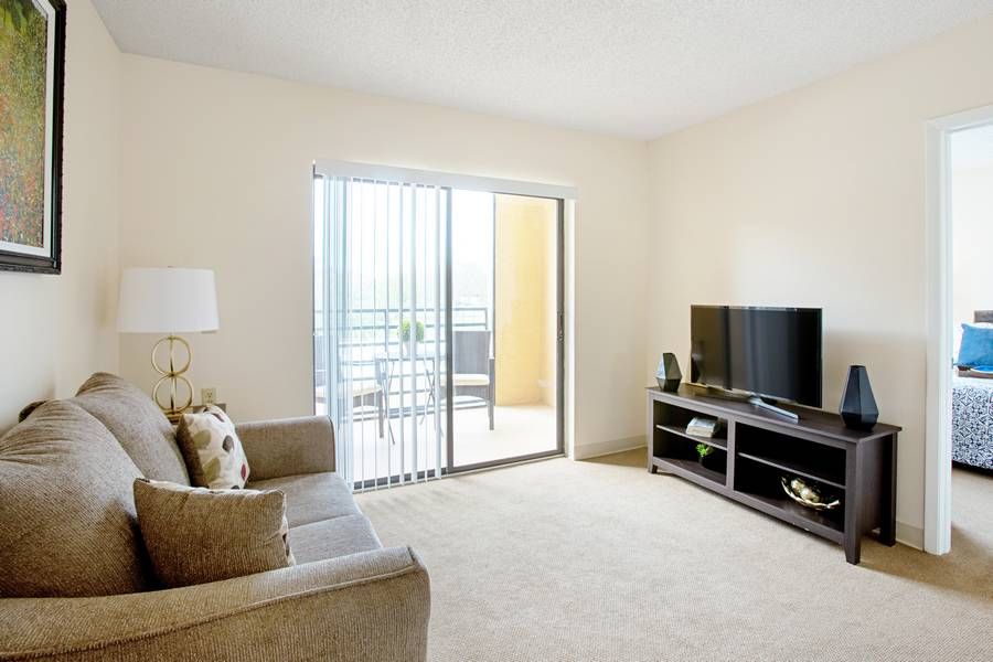 A cozy living room with a sofa, TV, and access to a balcony.