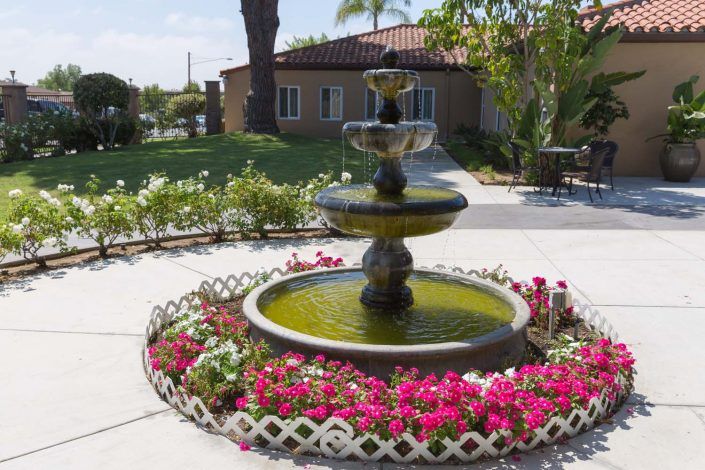 A beautiful garden with a tiered fountain surrounded by vibrant flowers.