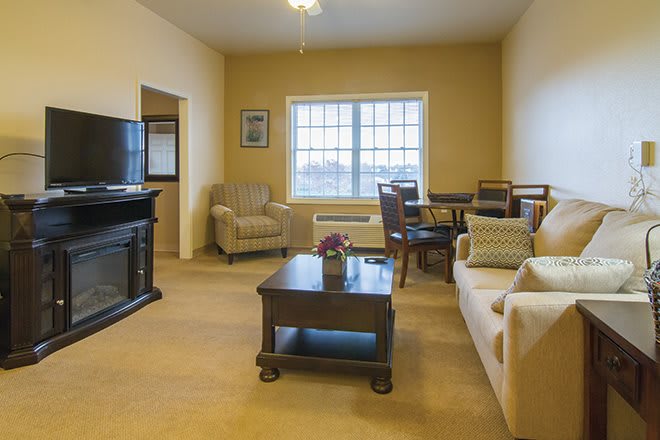 A cozy living room featuring a sofa, armchair, and dining area with warm lighting.