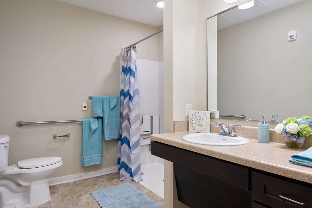 A clean and modern bathroom featuring a sink, mirror, shower curtain, and neatly hung towels.