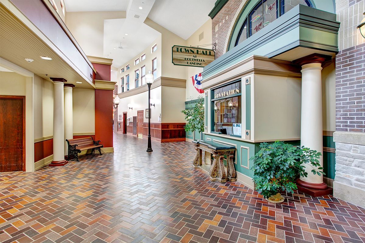 A vintage-style indoor arcade featuring a brick floor and shopfronts with decorative elements.