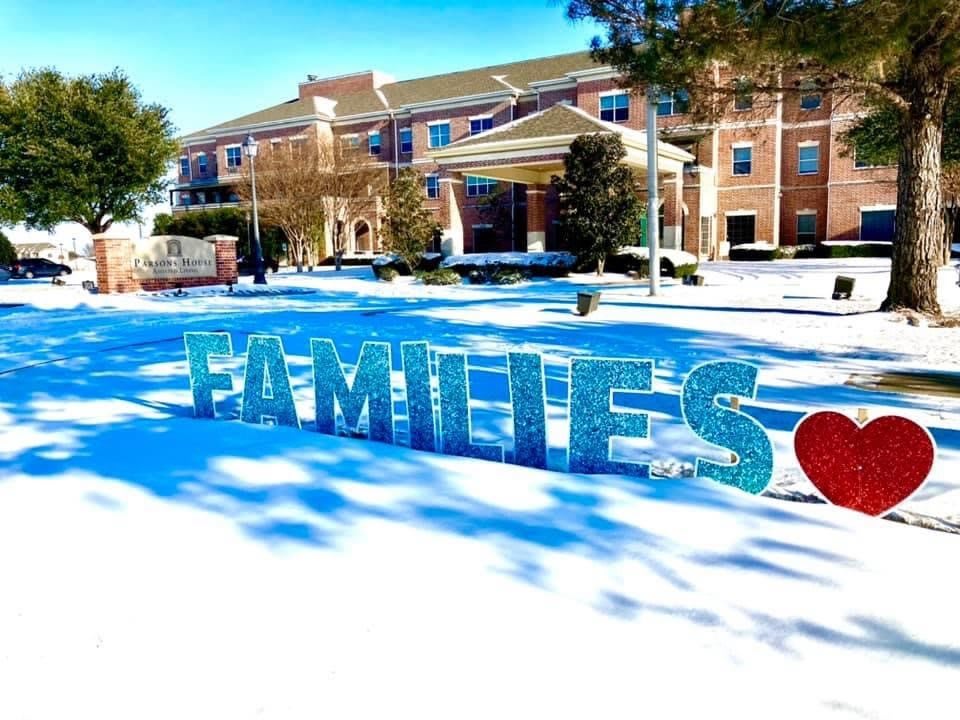A winter scene featuring a 'FAMILIES' sign in front of a building covered in snow.