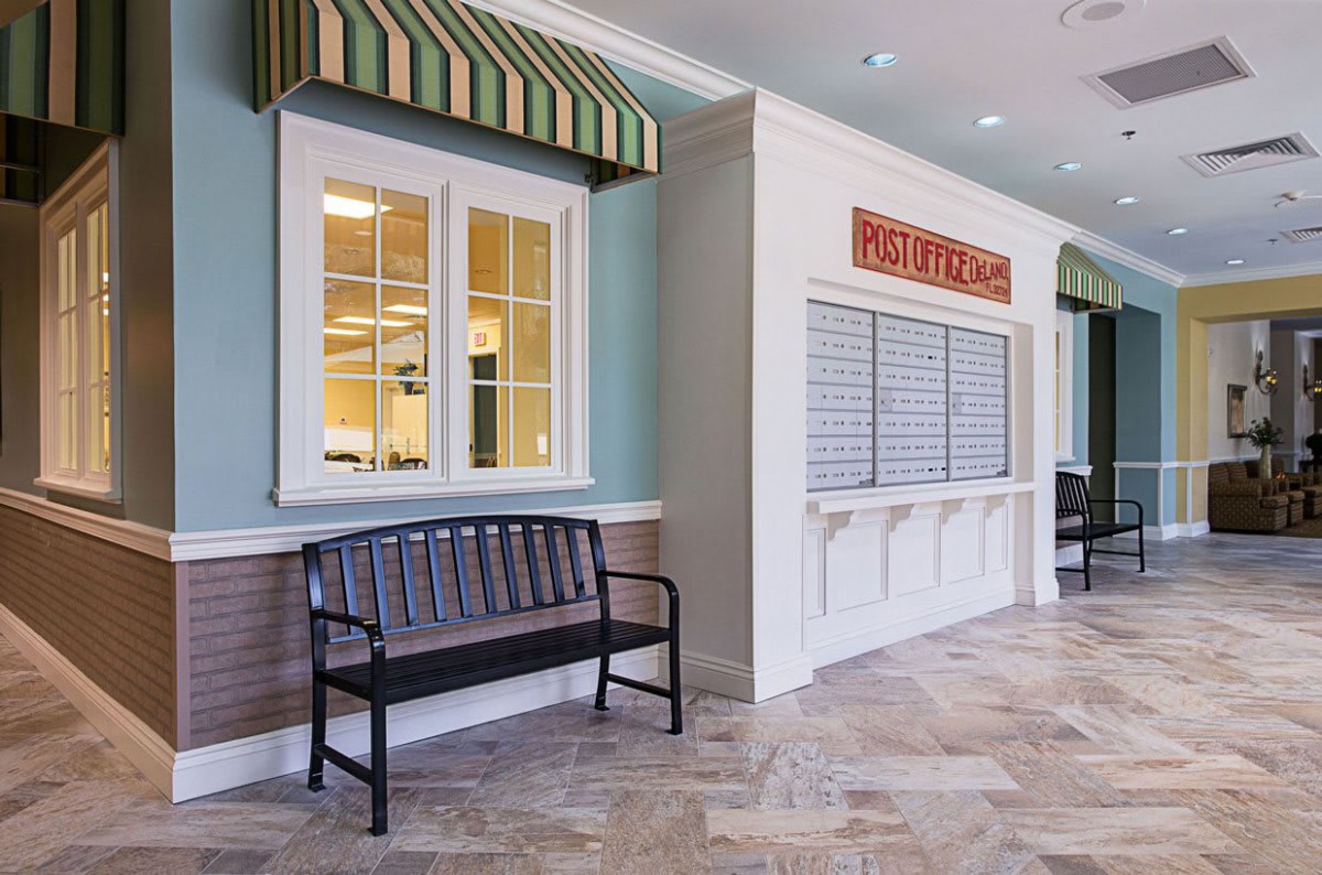 An indoor setting with a bench, window with striped awning, and a closed service counter.