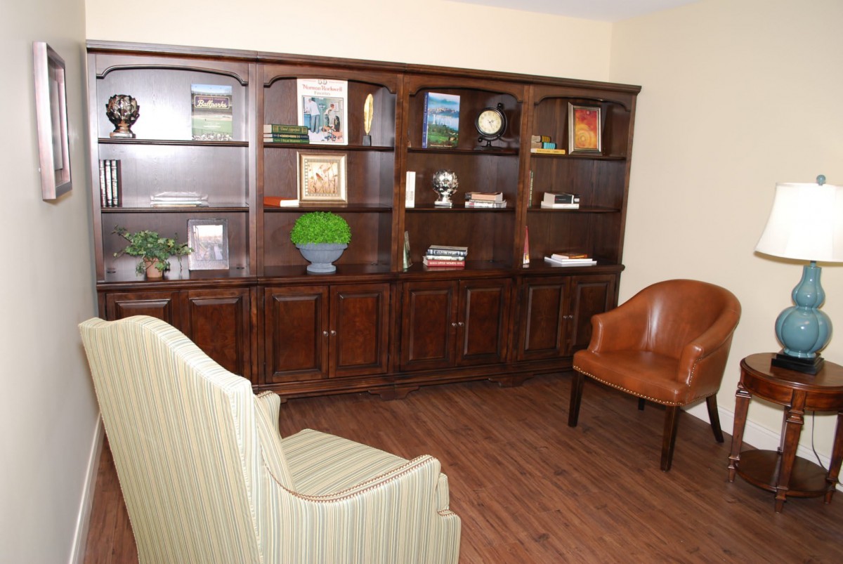 A cozy living room with a wooden bookshelf and comfortable armchairs.