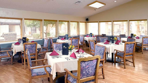 A cozy restaurant dining area featuring elegantly set tables with decorative napkins and a bright, airy atmosphere.