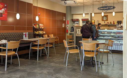 A cozy cafe setting with wooden tables and chairs, featuring customers at the counter.
