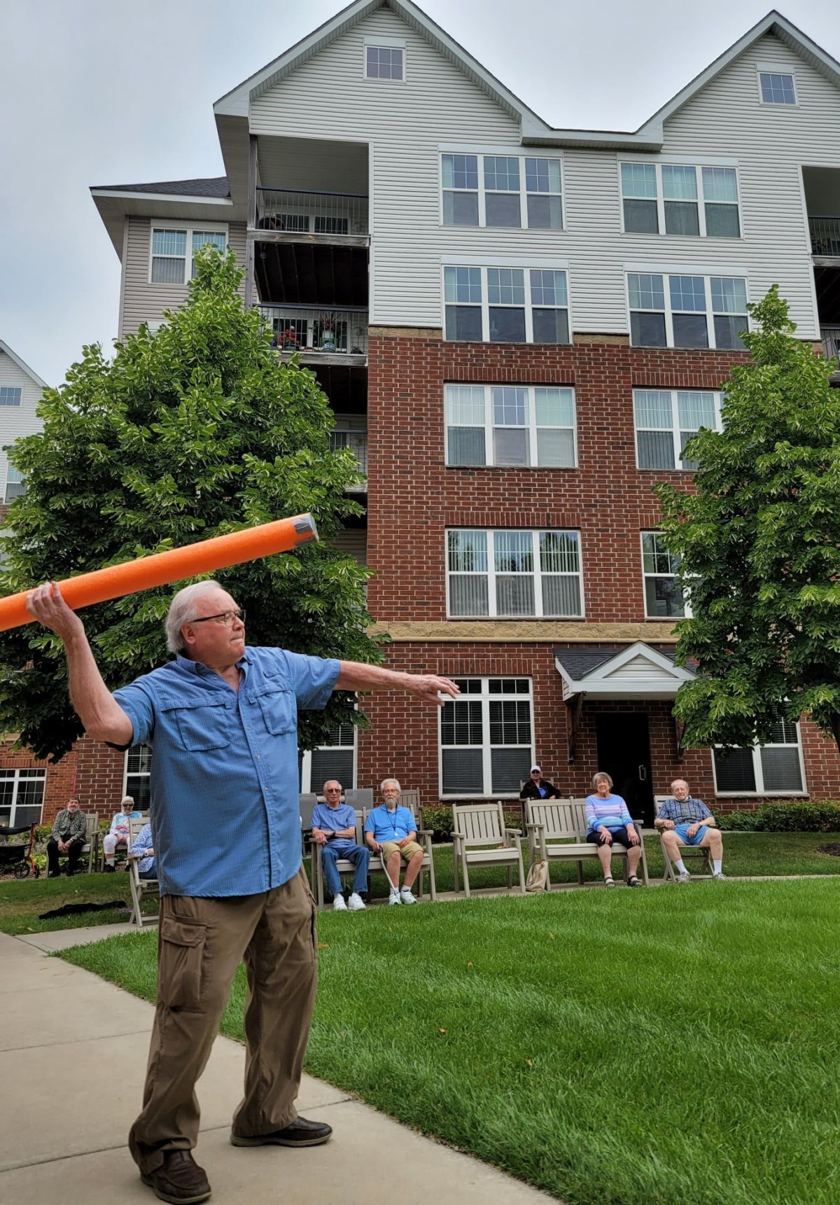 A group of seniors enjoying an outdoor activity in front of a multi-story building.