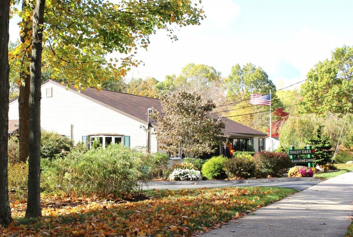 A peaceful building surrounded by autumn trees and foliage, with a sidewalk in the foreground.