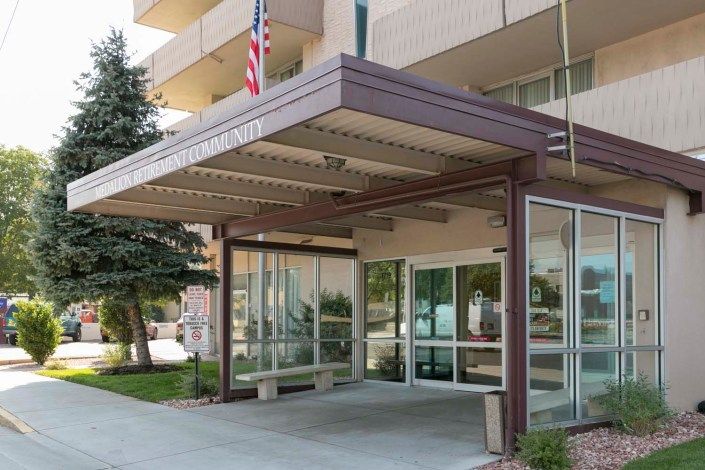 The entrance of a building with a modern canopy and glass doors, featuring an American flag on display.