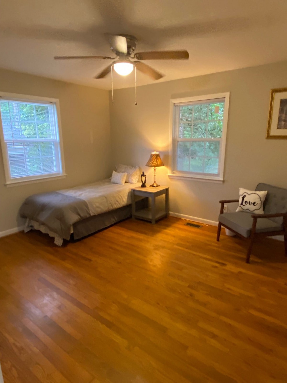 A minimalist bedroom with a single bed, wooden flooring, and a cozy chair.