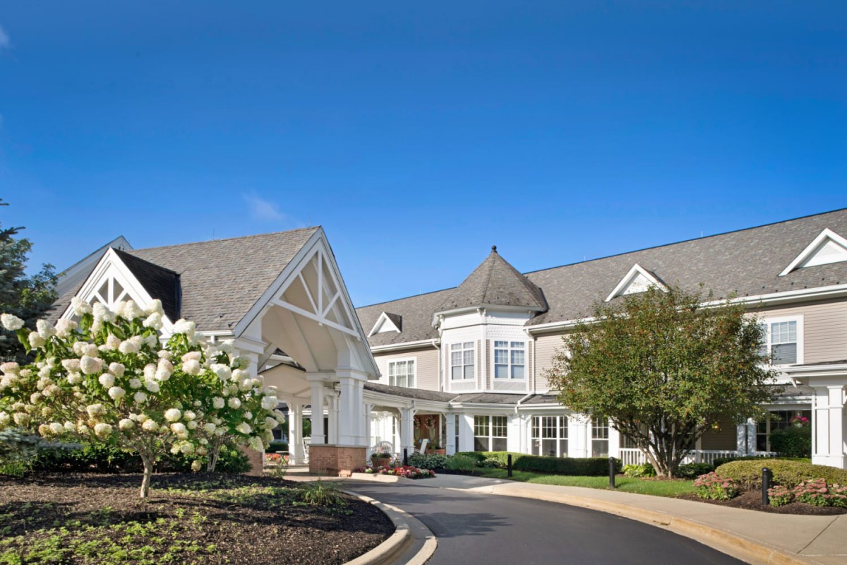 A large residence with a landscaped driveway and clear blue sky.
