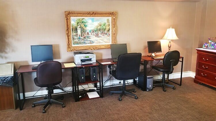 An office space with several workstations equipped with computers, a printer, and a decorative painting on the wall.