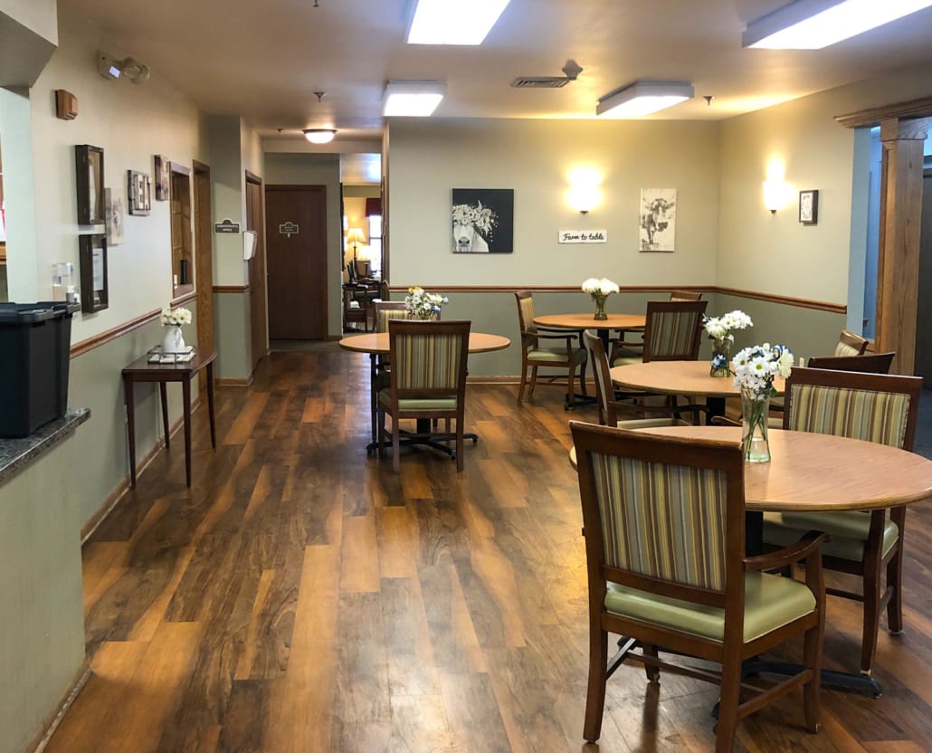 A cozy dining area with wooden floors and neatly arranged tables and chairs.