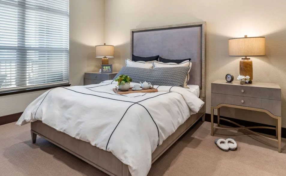 A cozy bedroom featuring a neatly made bed with pillows and modern bedside lamps.