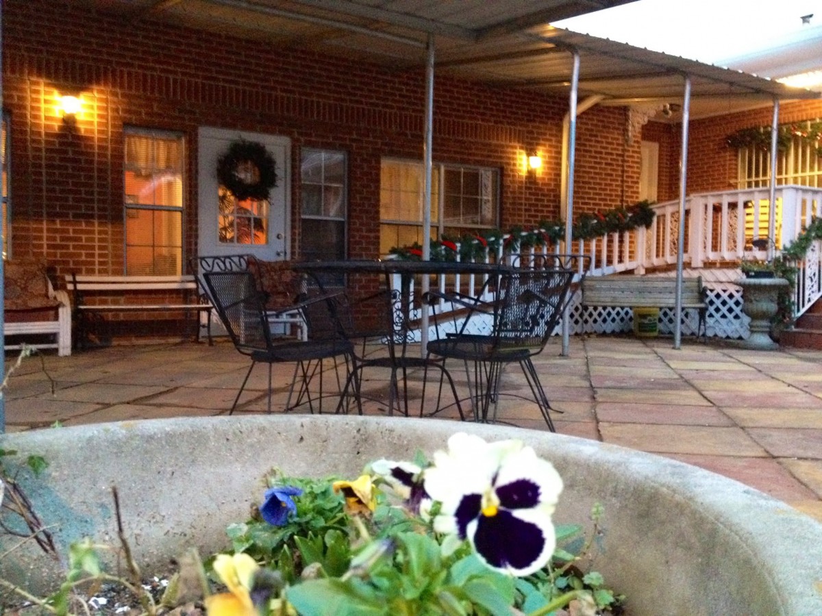 A cozy patio with a table and chairs, adorned with pansy flowers and evening lighting.