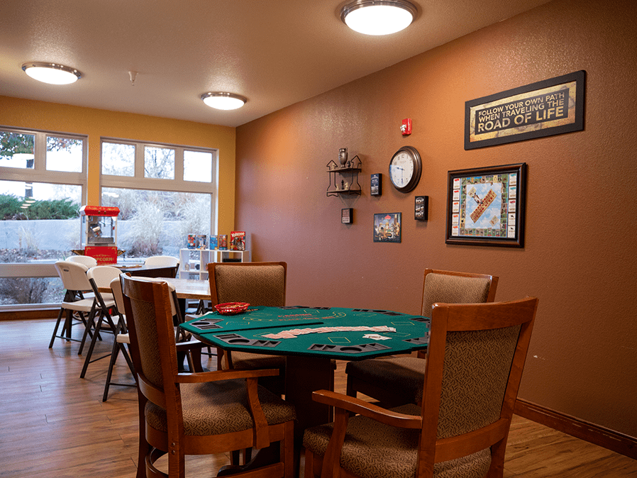 A cozy game room featuring a poker table surrounded by chairs, decorated with wall art and warm lighting.