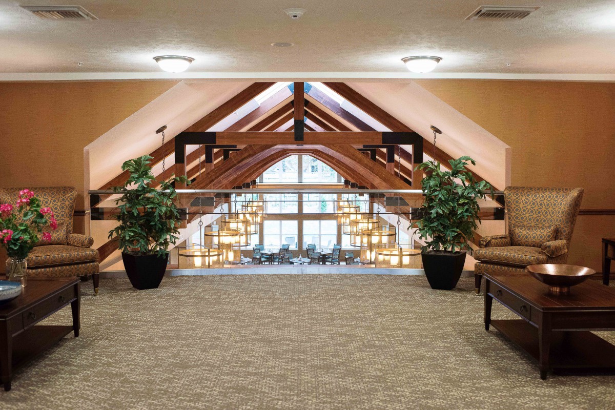 A spacious atrium with large glass windows, wooden beams, and a cozy seating area.