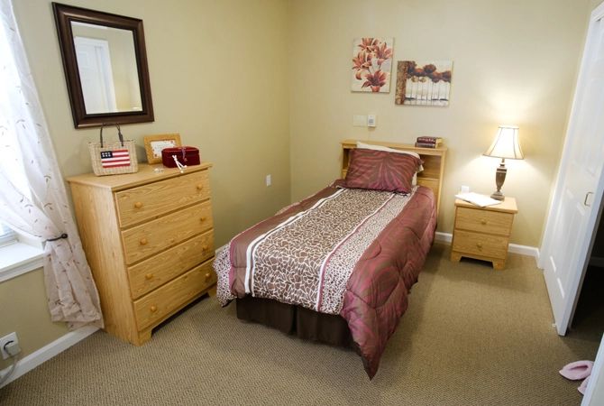 A neatly arranged bedroom with a single bed and wooden furniture.