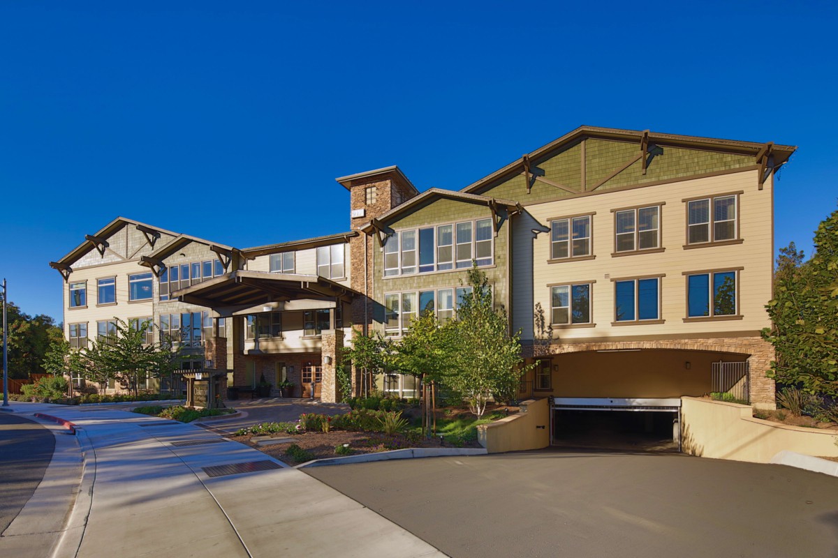 A modern residential building with well-maintained landscaping and a clear blue sky.