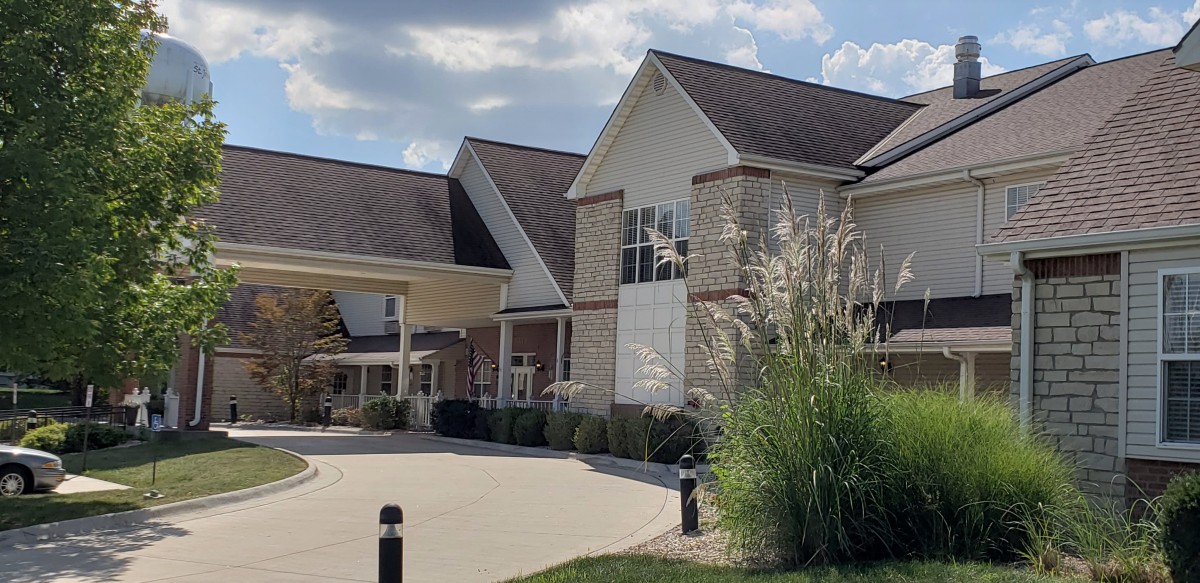 A modern building with a sloped roof and landscaped surroundings on a sunny day.