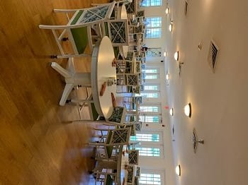 An empty dining area with neatly arranged tables and chairs under warm ceiling lights.
