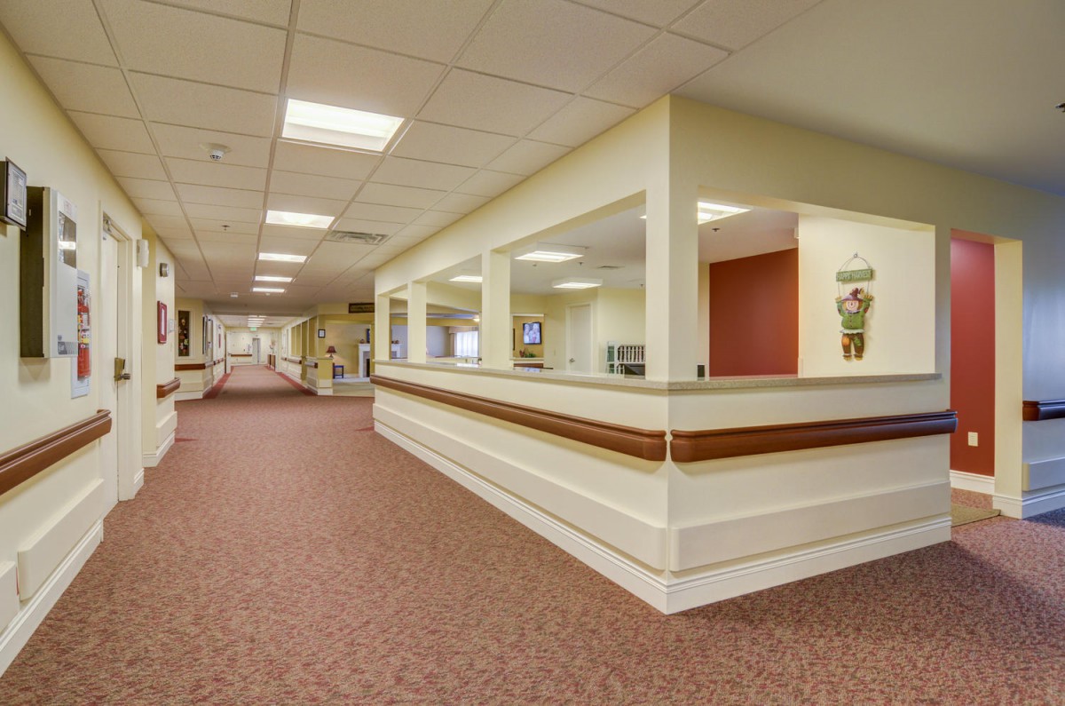 An empty office hallway with a reception desk and ceiling lights.