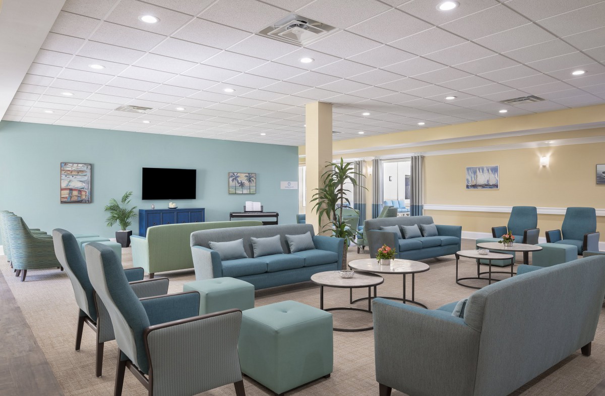 A spacious and modern lounge area with comfortable seating, a television, and decorative plants.