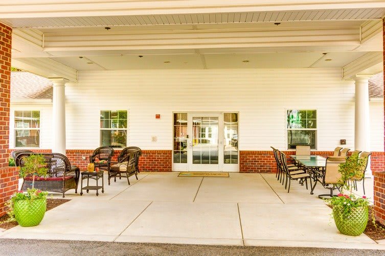 An inviting building entrance with outdoor seating under a covered patio.