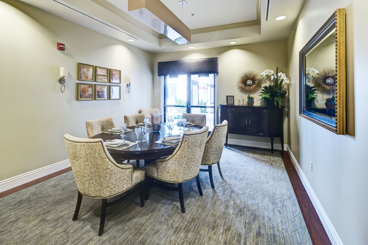 A modern dining room with a round table and upholstered chairs, featuring elegant decor.