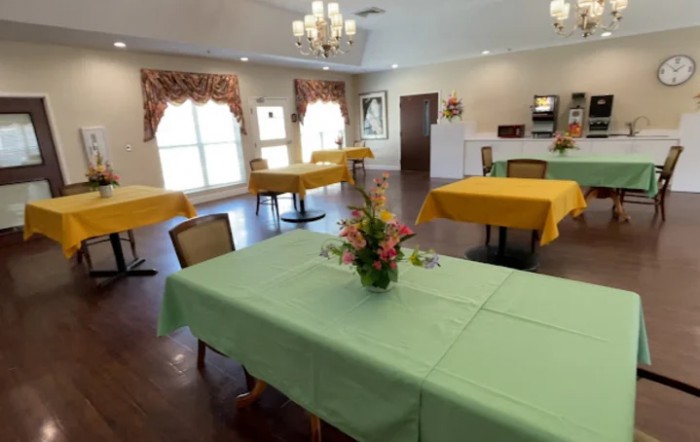 A tidy dining room with colorful tablecloths and floral centerpieces.