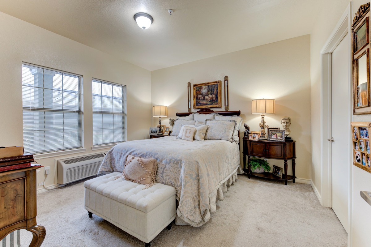 A cozy bedroom with a neatly made bed, nightstands, and soft lighting.