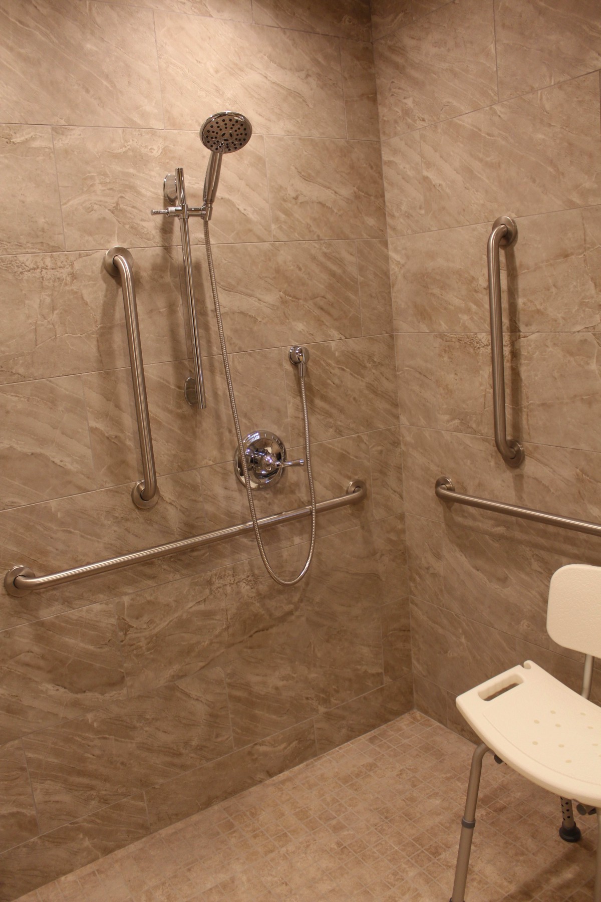 An accessible shower with grab bars and a shower chair for improved safety and convenience.