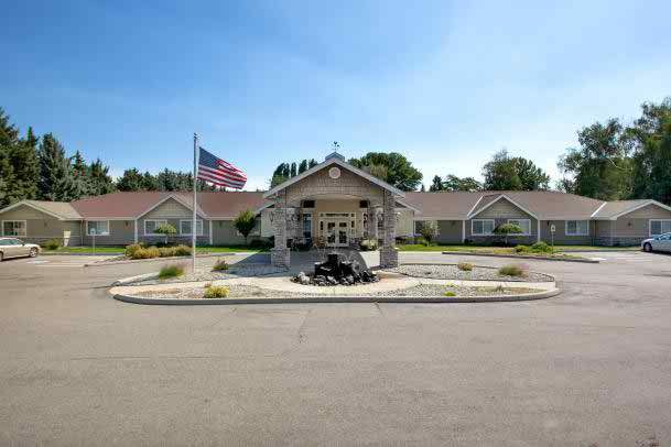 A residential building with an American flag at the entrance, surrounded by a driveway and landscaped area.
