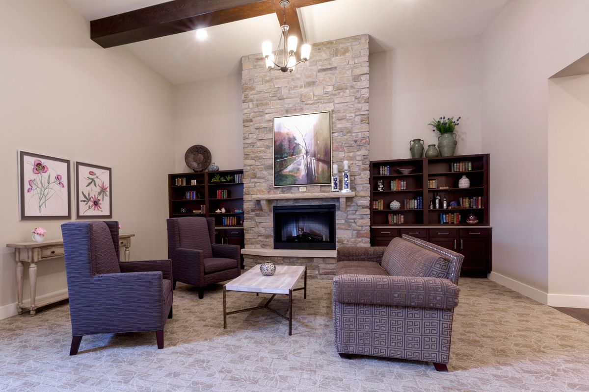 A cozy living room featuring a fireplace, armchairs, and bookshelves with modern decor accents.