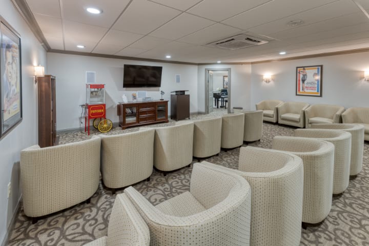 A modern conference room with rows of comfortable chairs facing a television and presentation area.
