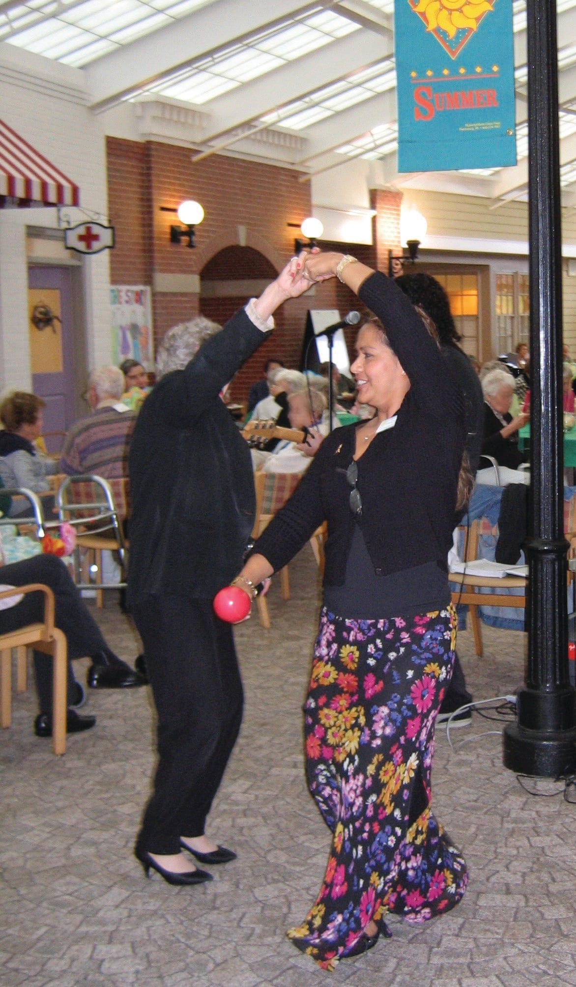 Two people dancing together in a social setting, surrounded by others.