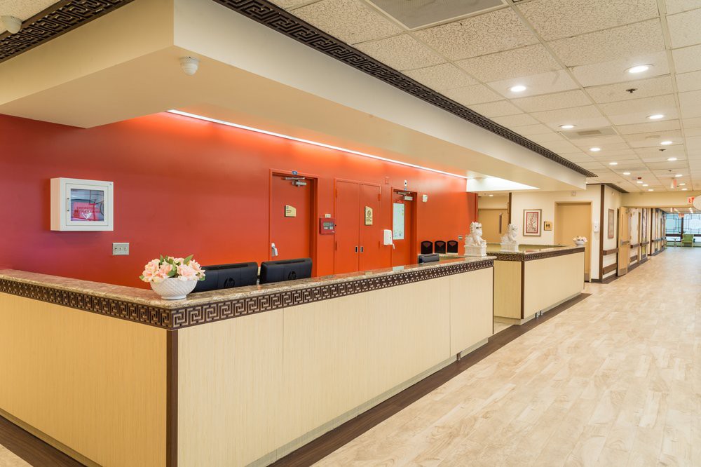 A modern hotel reception area with a red accent wall and a long front desk.