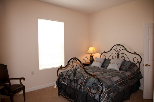 A cozy and well-lit bedroom featuring an iron bed with comfortable bedding and a bedside lamp.