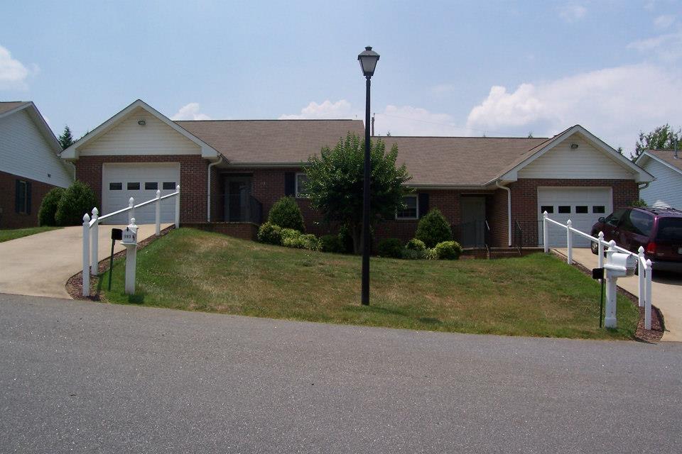 A suburban house with a driveway and garages on a sunny day.
