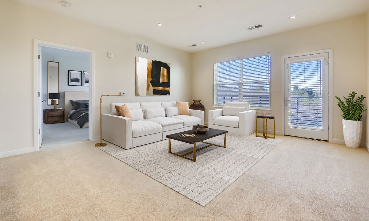 A modern living room with a cozy white sofa, armchair, and a stylish coffee table, beautifully lit by natural light through large windows.