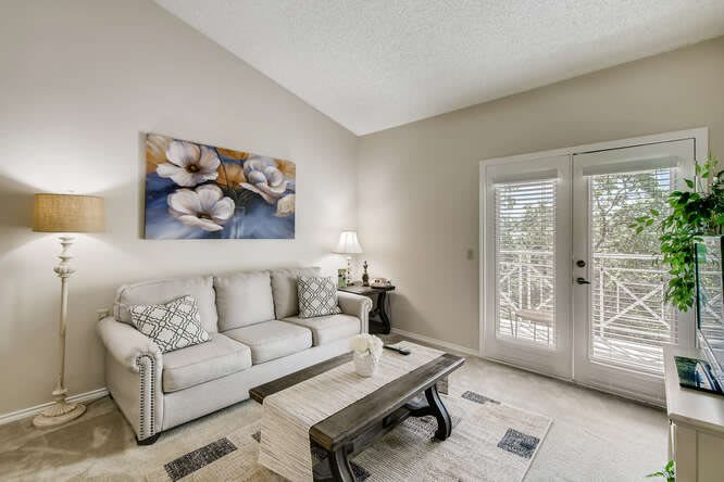 A cozy living room with a white sofa, floral artwork, and a wooden coffee table.